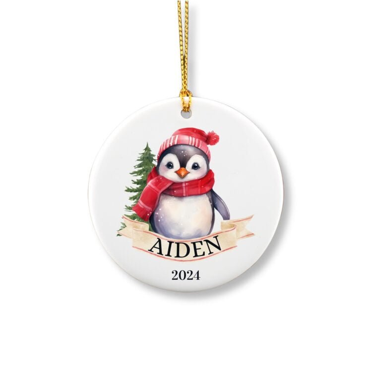 Personalized Penguin ornament with name and winter hat in front of a tree